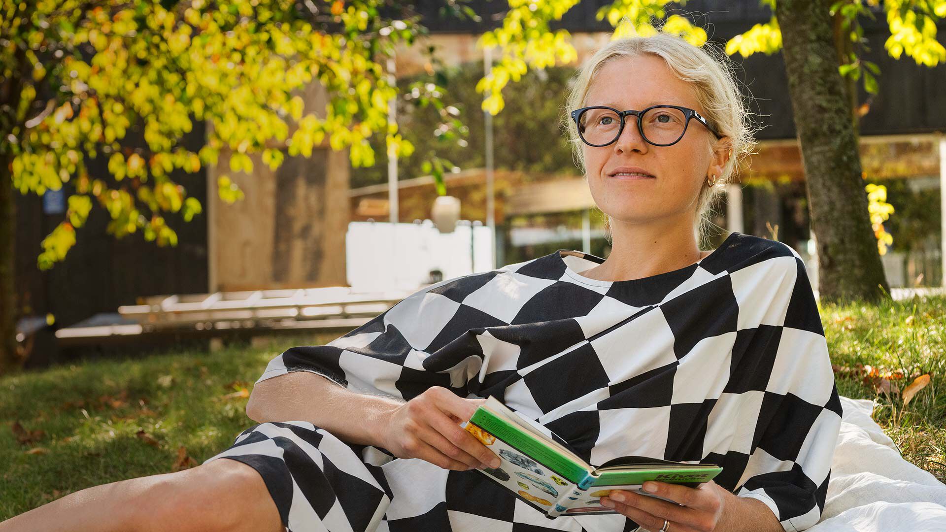 Nainen makaa piknikill&auml;, kirja k&auml;dess&auml;&auml;n